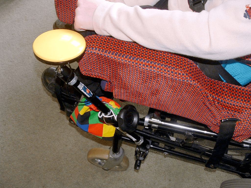 Duży pojedynczy przycisk sterujący, umocowany z boku wózka inwalidzkiego.